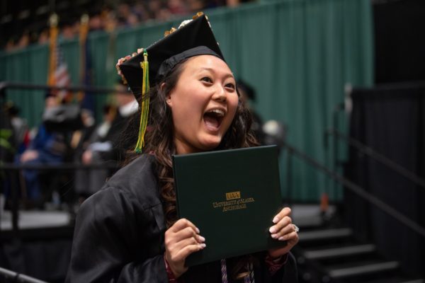 Jacqueline Yi, B.S. Nursing Science, shows off her degree during UAA's 2019 Fall Commencement at the Alaska Airlines Center.